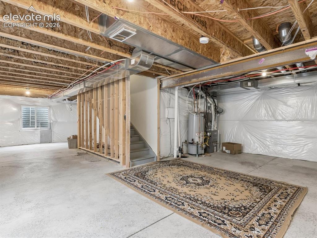 Image 18 of 23: Unfinished basement space featuring exposed wood joists and concrete floori