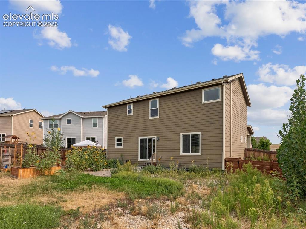 Image 19 of 23: Rear elevation with tan siding and white trim windows