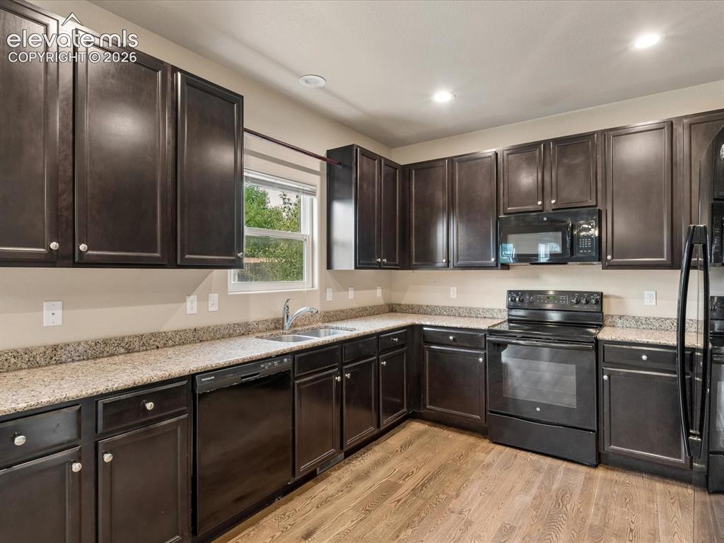 Image 3 of 23: Modern kitchen featuring dark wood-finish cabinetry, speckled countertops, 