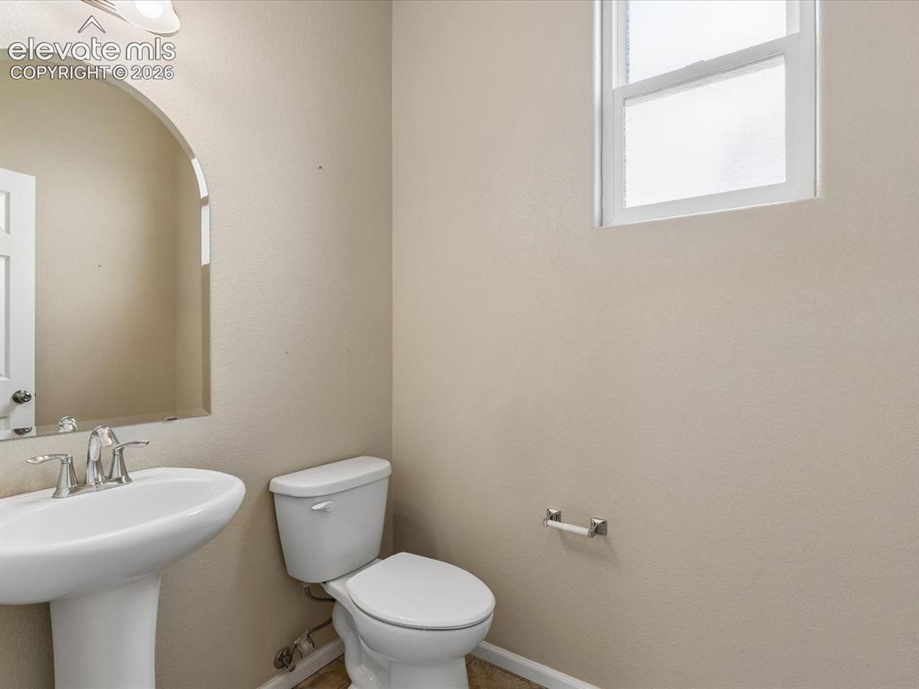 Image 8 of 23: Pedestal sink with chrome faucet, toilet, and arched mirror