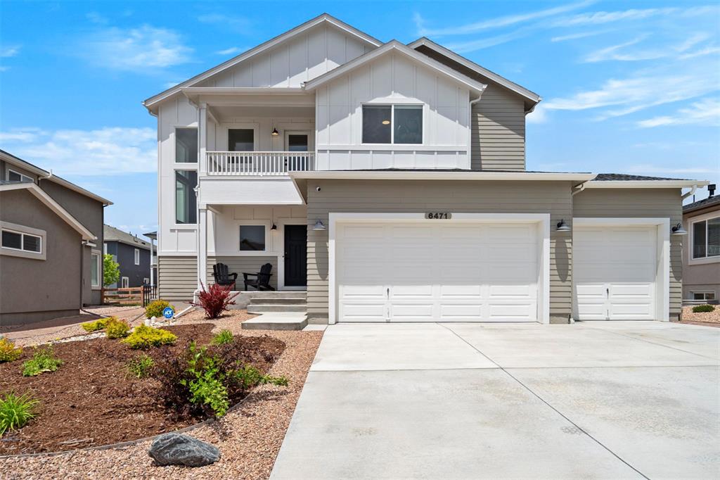 Caption: View of front facade featuring concrete driveway, a balcony, board and batten siding, a porch, and a