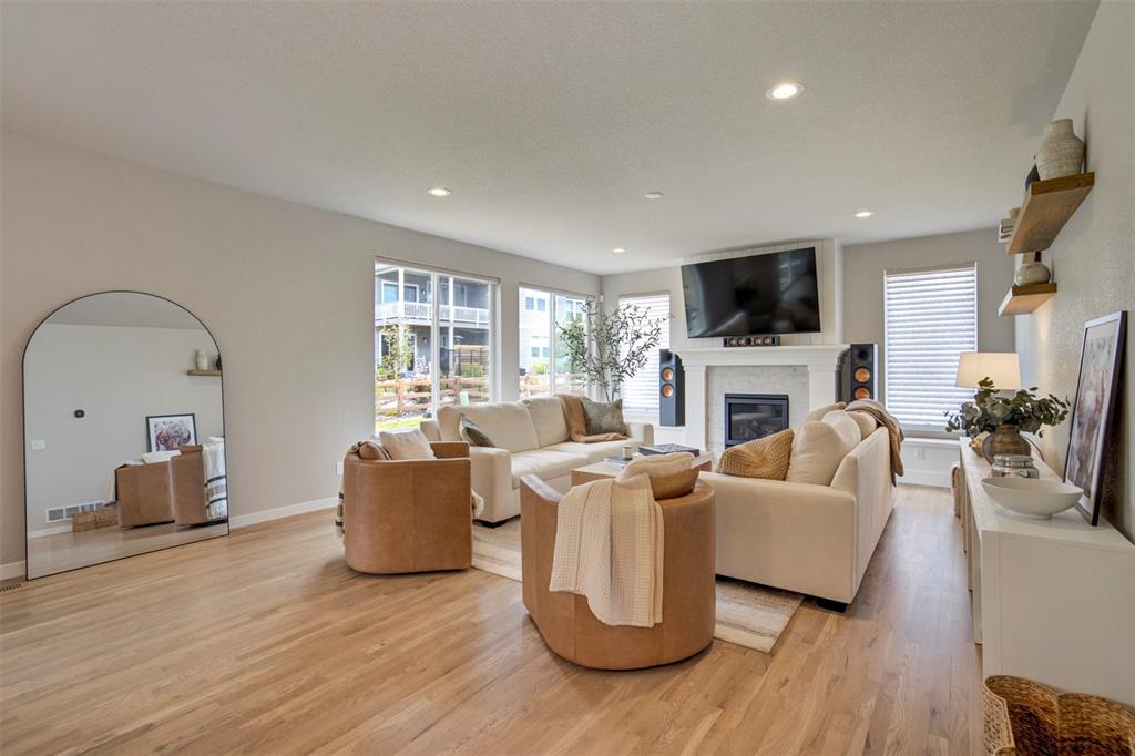 Image 11 of 43: Living area featuring a glass covered fireplace, light wood-style floors, h