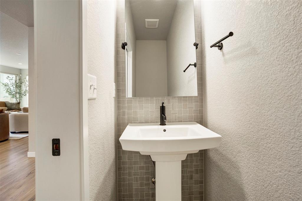 Image 14 of 43: Bathroom featuring decorative backsplash, a textured wall, and wood finishe
