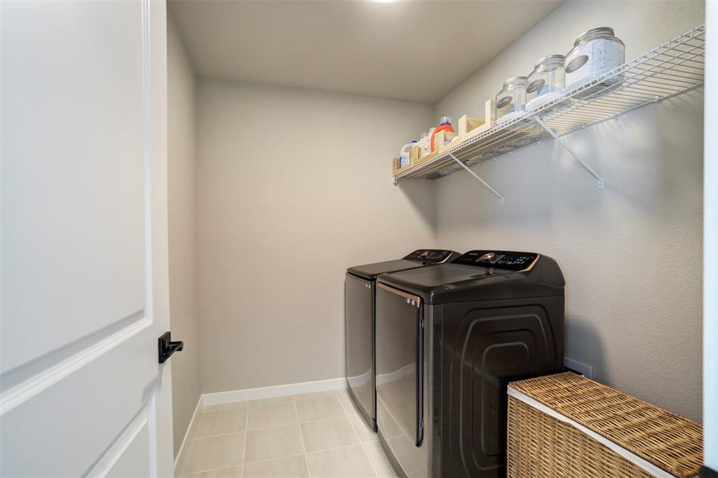 Image 19 of 43: Laundry area featuring separate washer and dryer and light tile patterned f