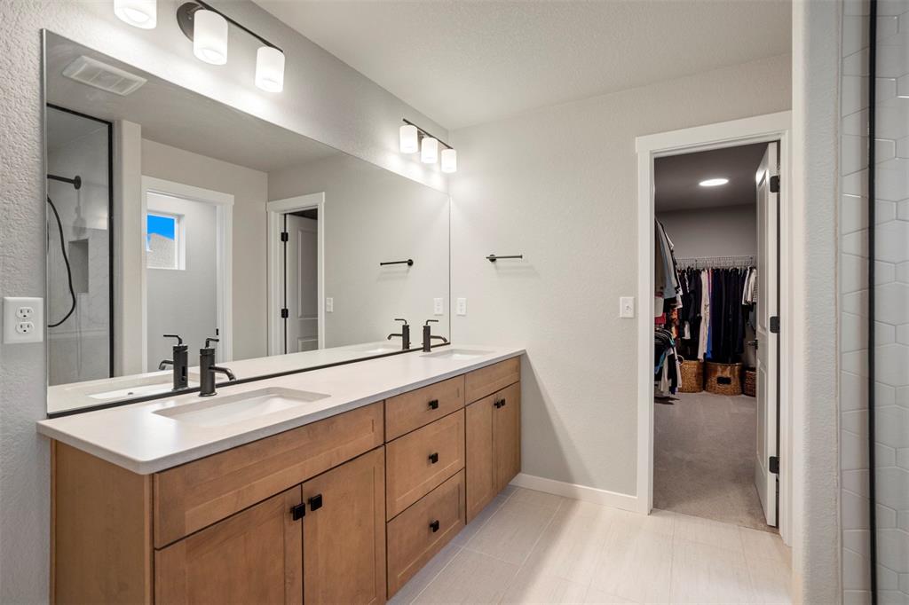 Image 24 of 43: Full bathroom featuring double vanity, a spacious closet, a shower, and lig