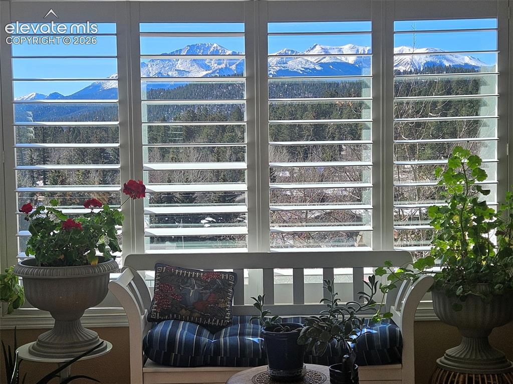 Image 5 of 45: Expansive windows featuring plantation shutters and a prominent mountain ba