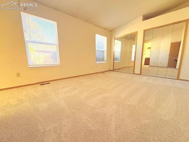 Image 10 of 28: Unfurnished bedroom featuring multiple closets, carpet flooring, and vaulte