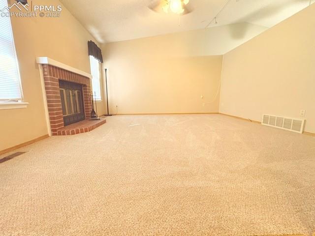 Image 4 of 28: Unfurnished living room featuring lofted ceiling, a fireplace, carpet floor