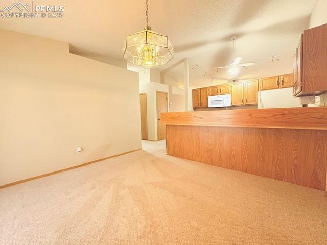 Image 8 of 28: Kitchen with decorative light fixtures, light carpet, a chandelier, white a