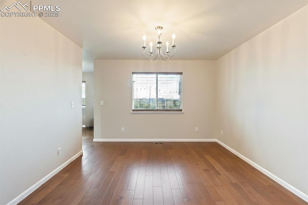Image 10 of 41: Unfurnished room with dark wood-style floors and a chandelier