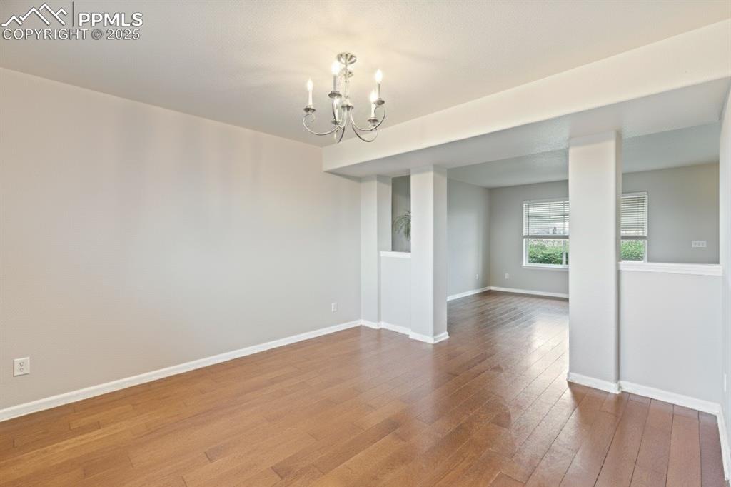 Image 11 of 41: Unfurnished dining area with a chandelier and hardwood / wood-style floorin