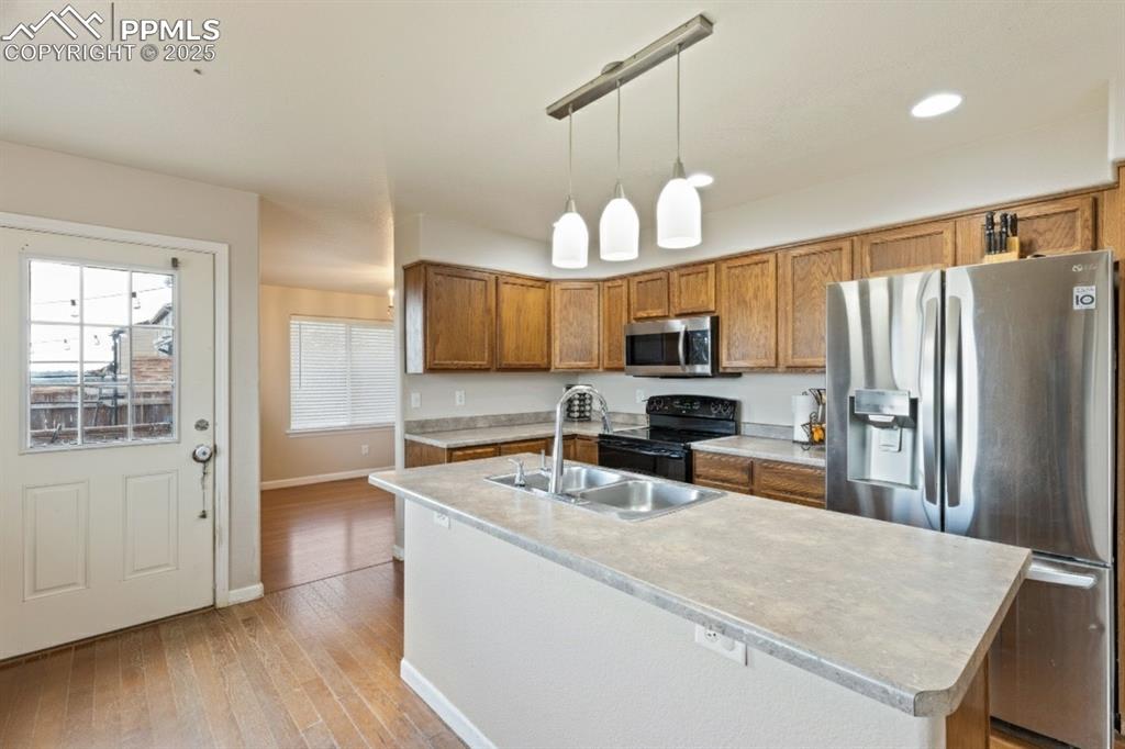 Image 13 of 41: Kitchen with appliances with stainless steel finishes, brown cabinetry, lig