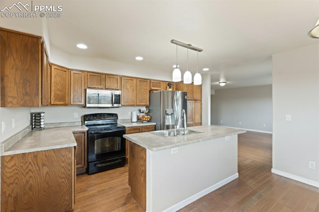Image 14 of 41: Kitchen with brown cabinetry, appliances with stainless steel finishes, dec