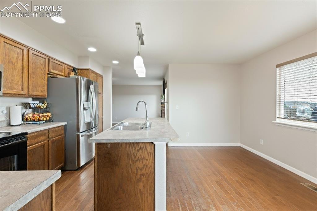Image 15 of 41: Kitchen with brown cabinets, a kitchen island with sink, recessed lighting,