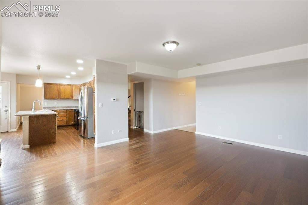 Image 17 of 41: Unfurnished living room with dark wood-style floors and recessed lighting
