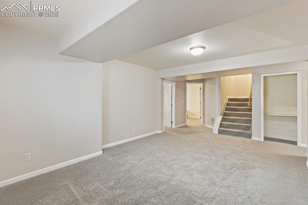 Image 27 of 41: Finished basement featuring light colored carpet and stairway