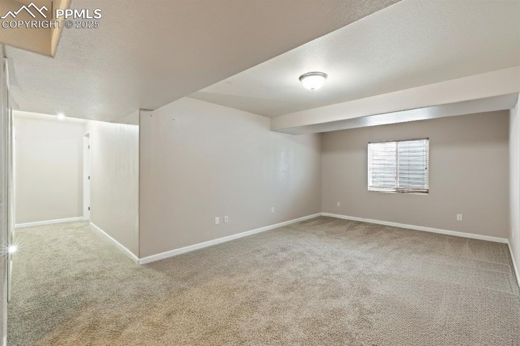 Image 28 of 41: Basement featuring a textured ceiling and light colored carpet