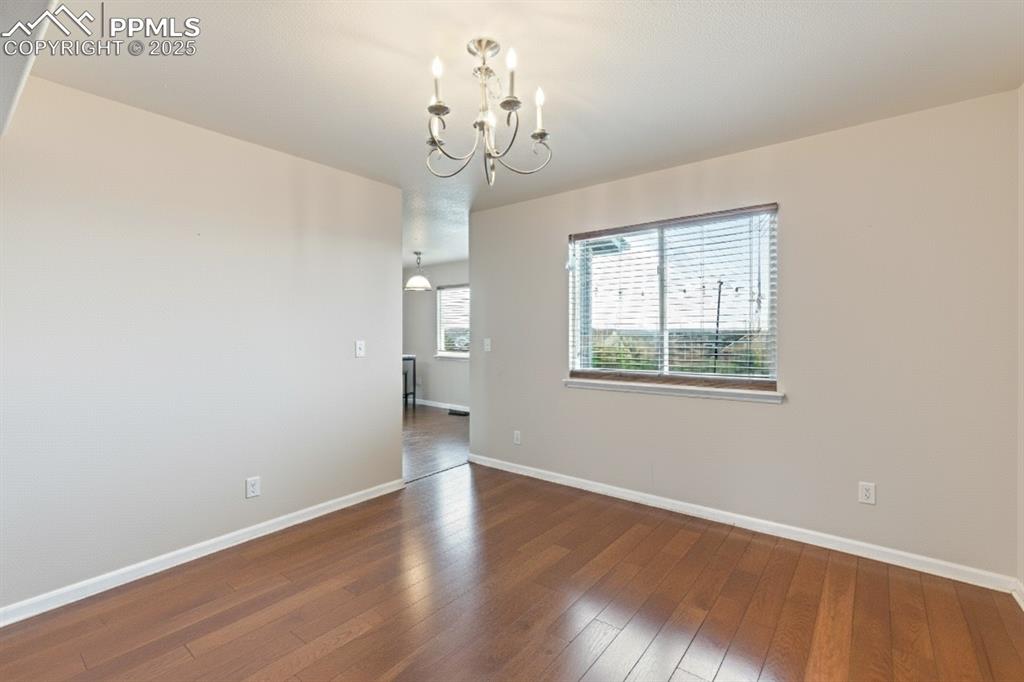 Image 9 of 41: Spare room with dark wood finished floors and a chandelier