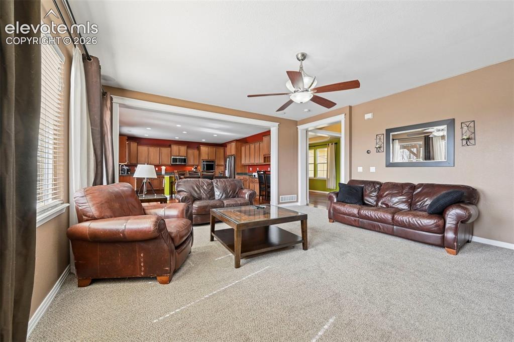 Image 2 of 45: Carpeted living area featuring a ceiling fan with integrated lighting, a br