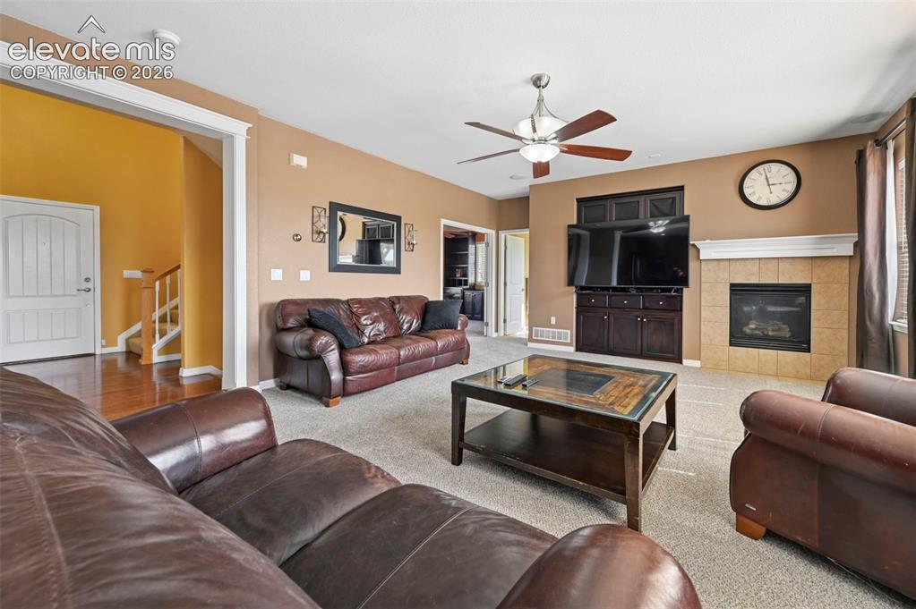Image 5 of 45: Living area featuring a gas fireplace with tile surround, built-in media ca