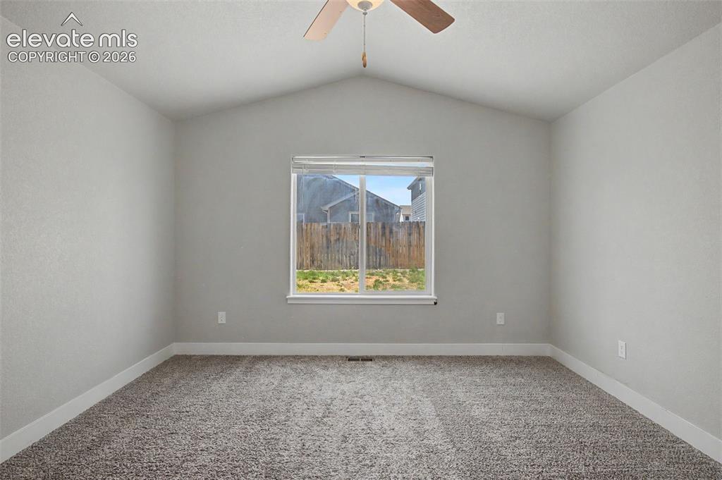 Image 23 of 44: Bright bedroom featuring vaulted ceilings, a central window, neutral carpet