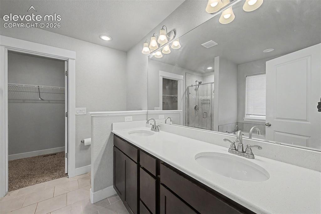 Image 24 of 44: Dual vanity with white countertops and dark wood cabinetry