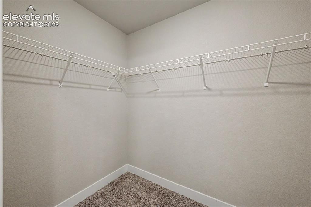 Image 26 of 44: Corner closet with wire shelving system, textured wall finish, white basebo