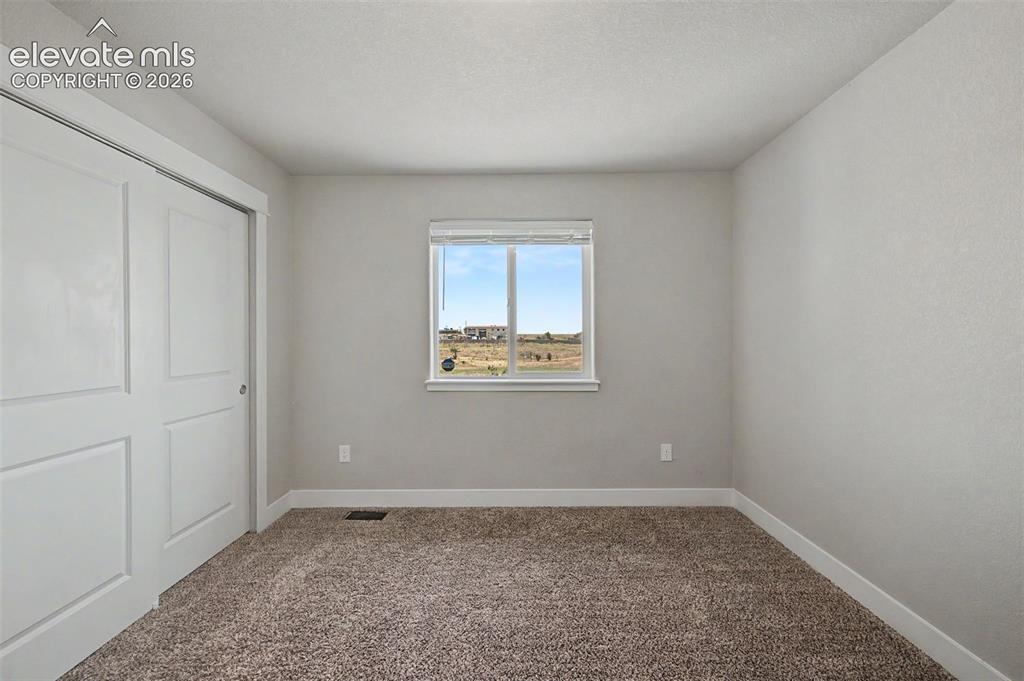 Image 28 of 44: Neutral wall paint, brown textured carpet, and white baseboards