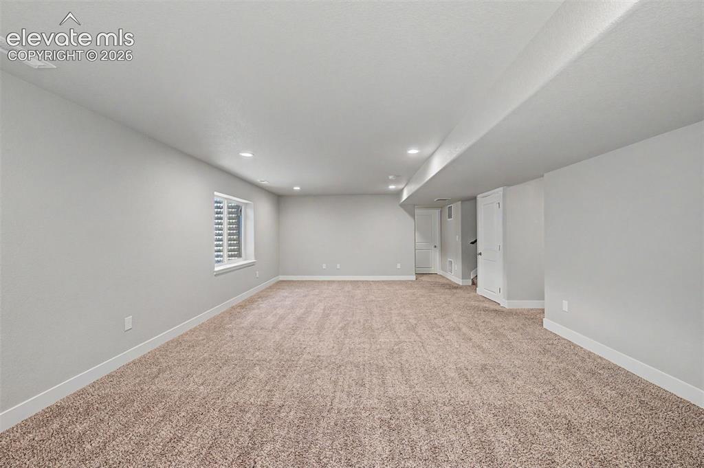 Image 32 of 44: Expansive carpeted area featuring recessed lighting, a single window with h