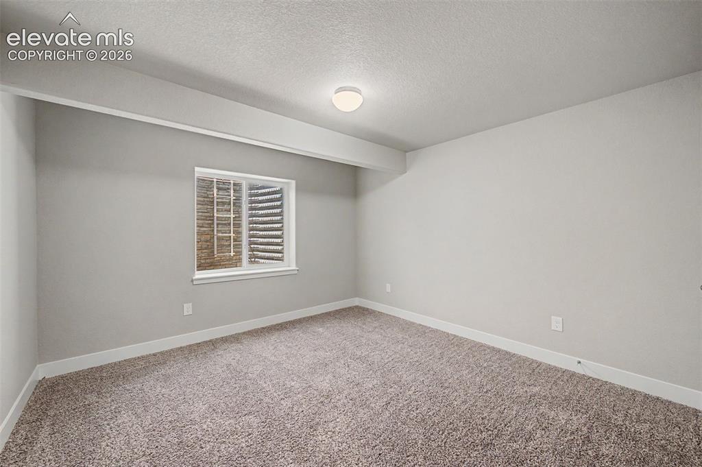 Image 35 of 44: Neutral-toned room featuring a window with security bars, light gray walls,