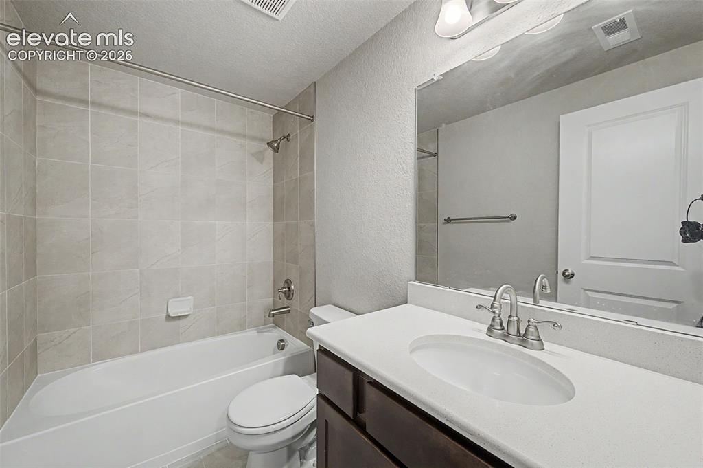 Image 37 of 44: Full bathroom featuring a single vanity with an undermount sink, dark wood-
