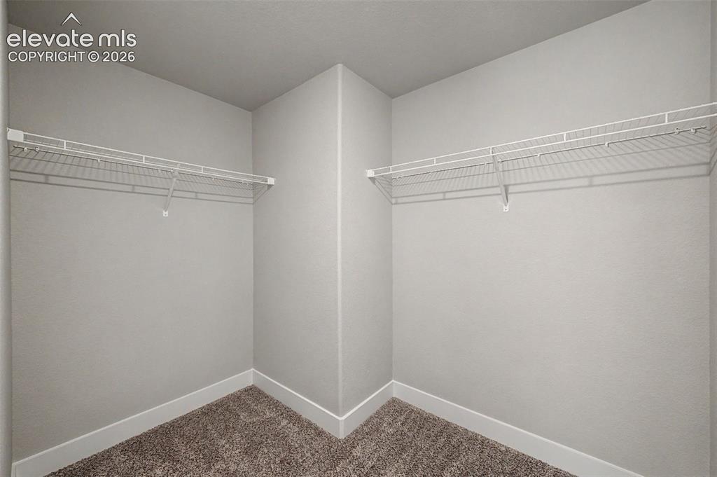 Image 40 of 44: Walk-in closet featuring light gray walls, white baseboards, and textured c
