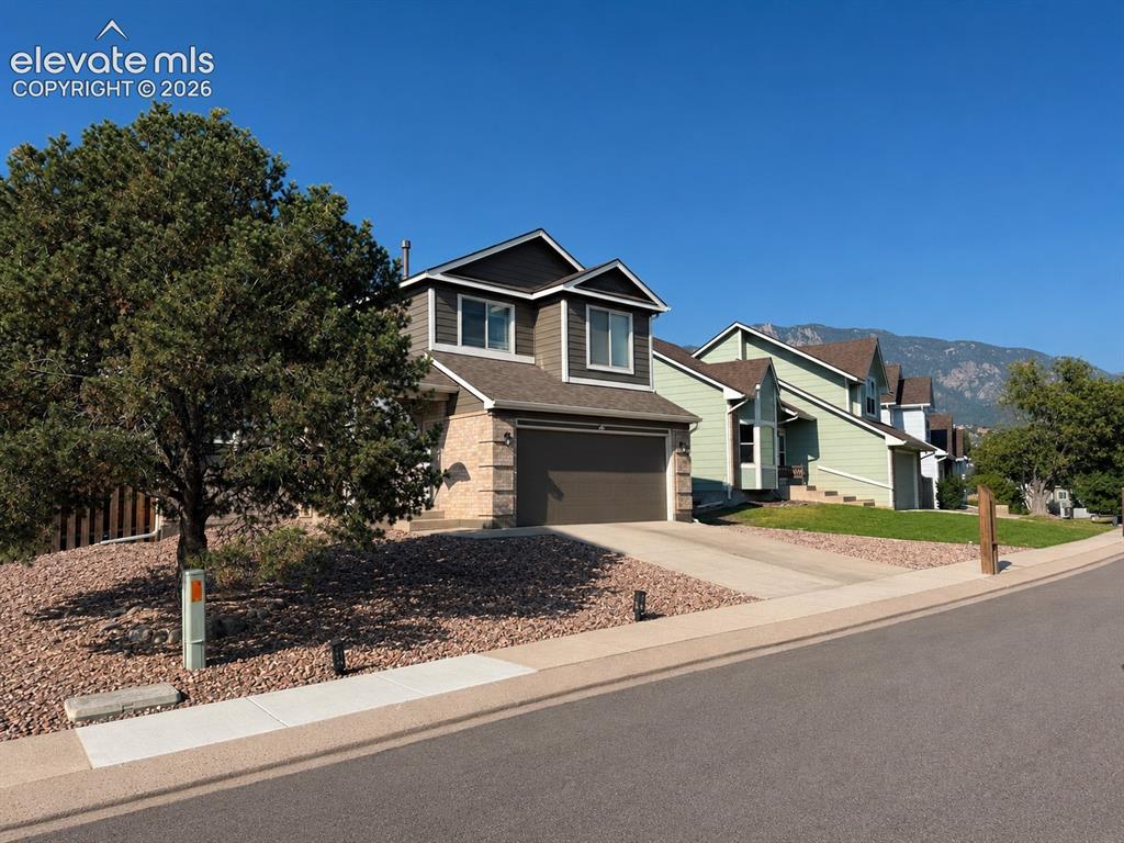 Caption: Contemporary two-story exterior with a two-car garage, partial stone facade, and concrete driveway
