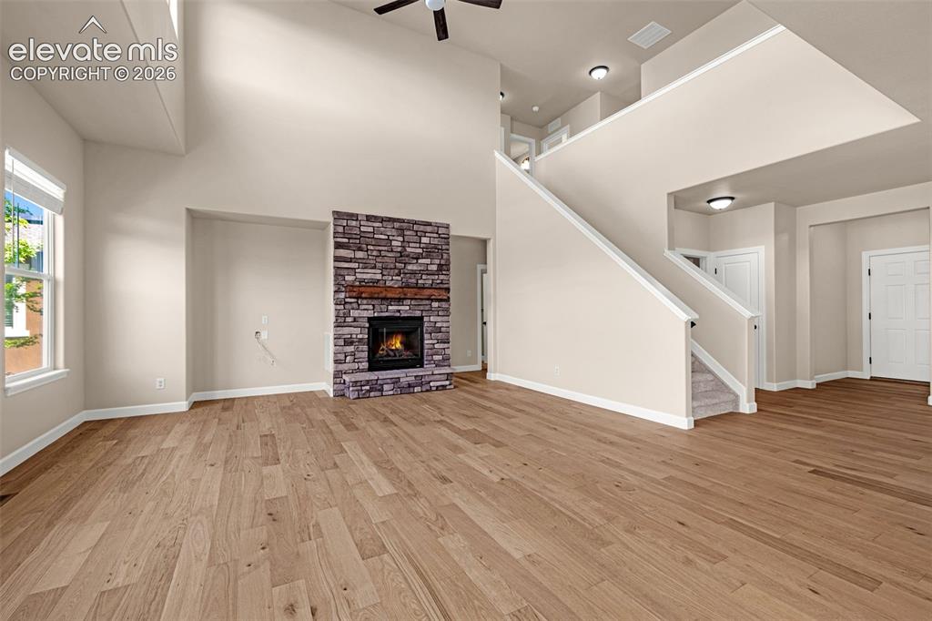 Image 10 of 42: Great room is bright and open. Gas fireplace with stone surround and wood