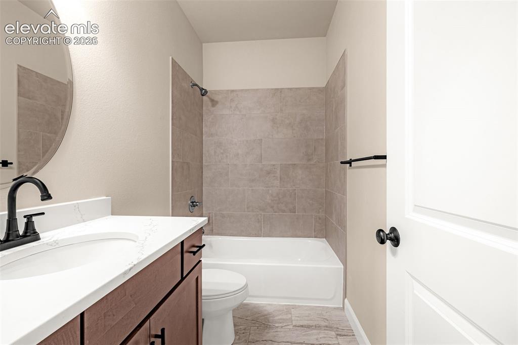 Image 13 of 42: Main level full bathroom with updated flooring, tile, cabinets, quartz coun