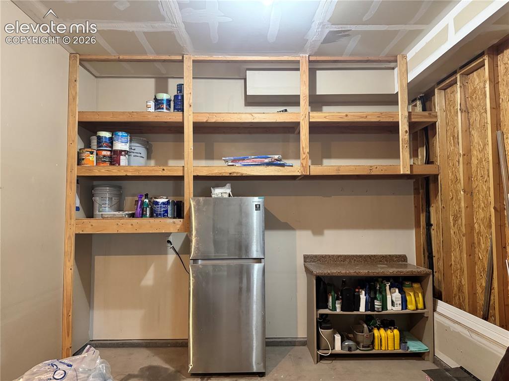 Image 36 of 42: 3 car tandem garage has built in shelving and room for refrigerator. 