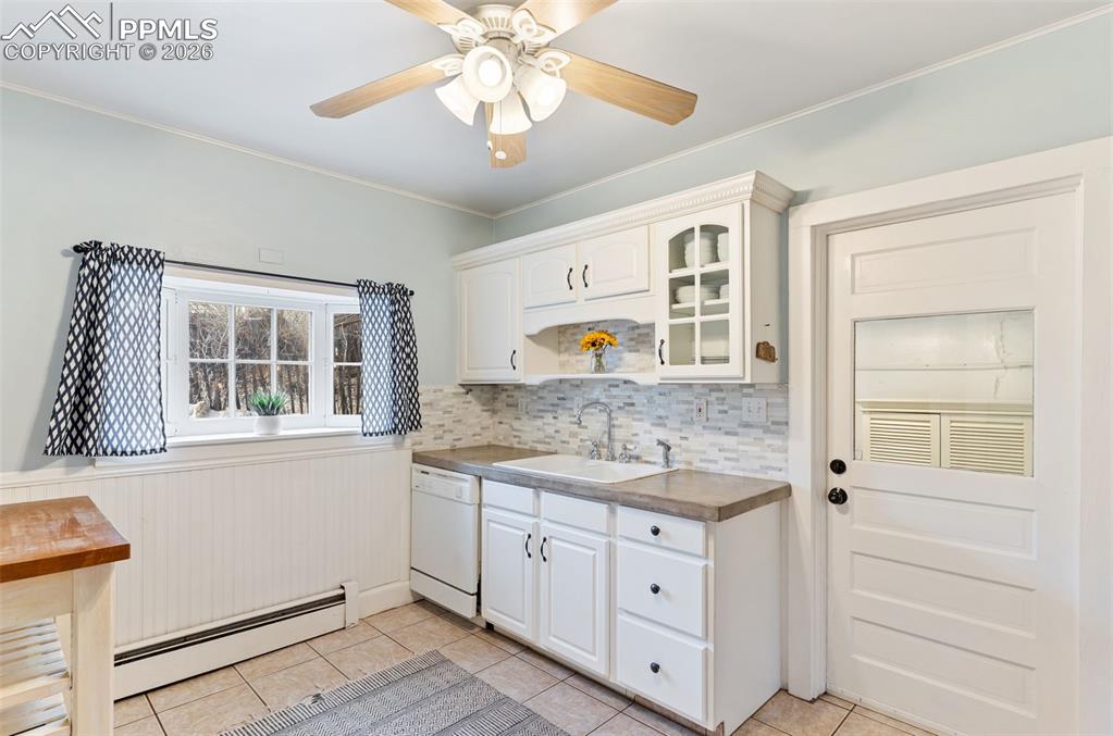 Image 14 of 36: Inviting kitchen with tile floor and door that leads out to laundry, storag