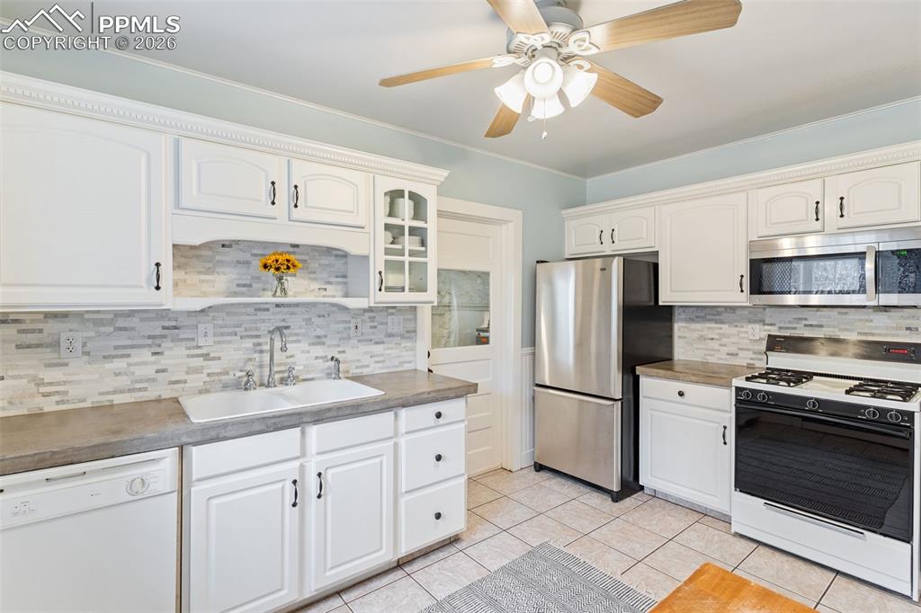 Image 15 of 36: Inviting kitchen with tile floor and door that leads out to laundry, storag