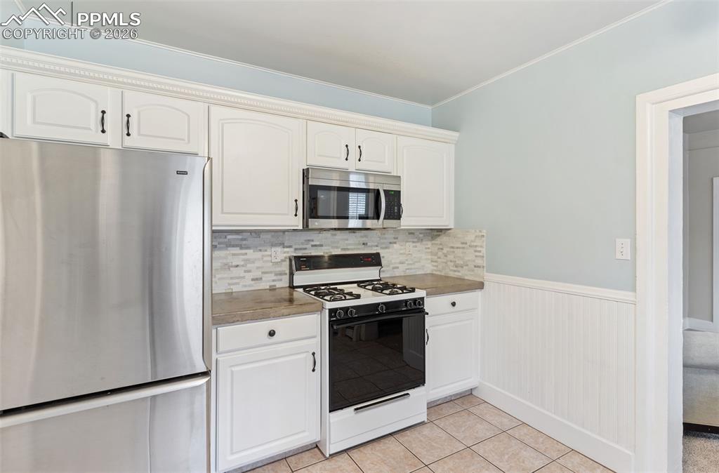 Image 16 of 36: Inviting kitchen with tile floor and door that leads out to laundry, storag