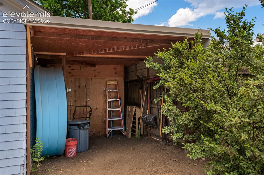 Image 45 of 50: Attached small carport with shed