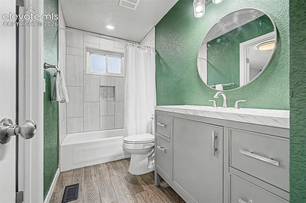 Image 15 of 44: Bathroom featuring a gray vanity with a stone countertop, a circular mirror