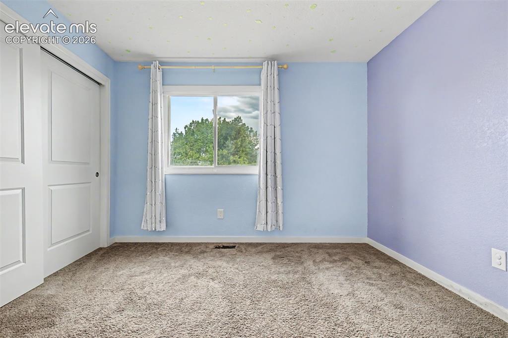 Image 17 of 44: Carpeted room featuring a white-trimmed window, sliding closet doors, and l