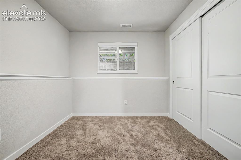 Image 25 of 44: Carpeted 3rd bedroom on the lower level features ample light, neutral walls