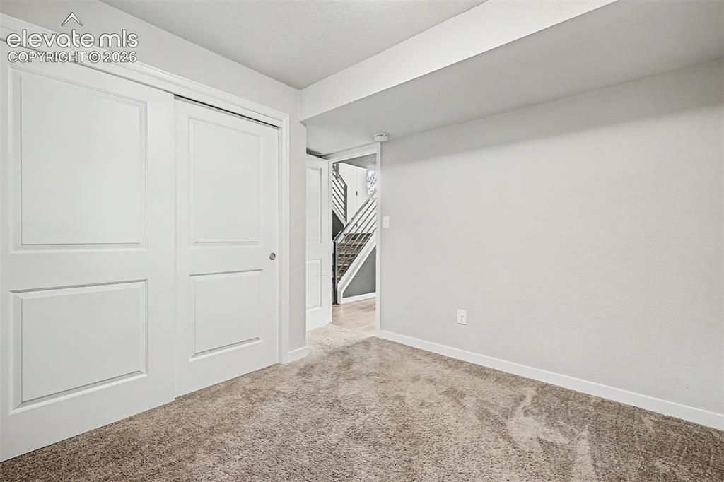 Image 26 of 44: Carpeted 3rd bedroom on the lower level features ample light, neutral walls
