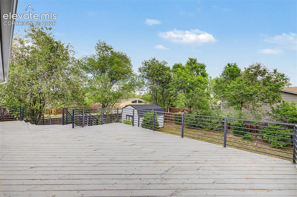 Image 30 of 44: Expansive wood deck with dark metal railings, offering multiple levels and 