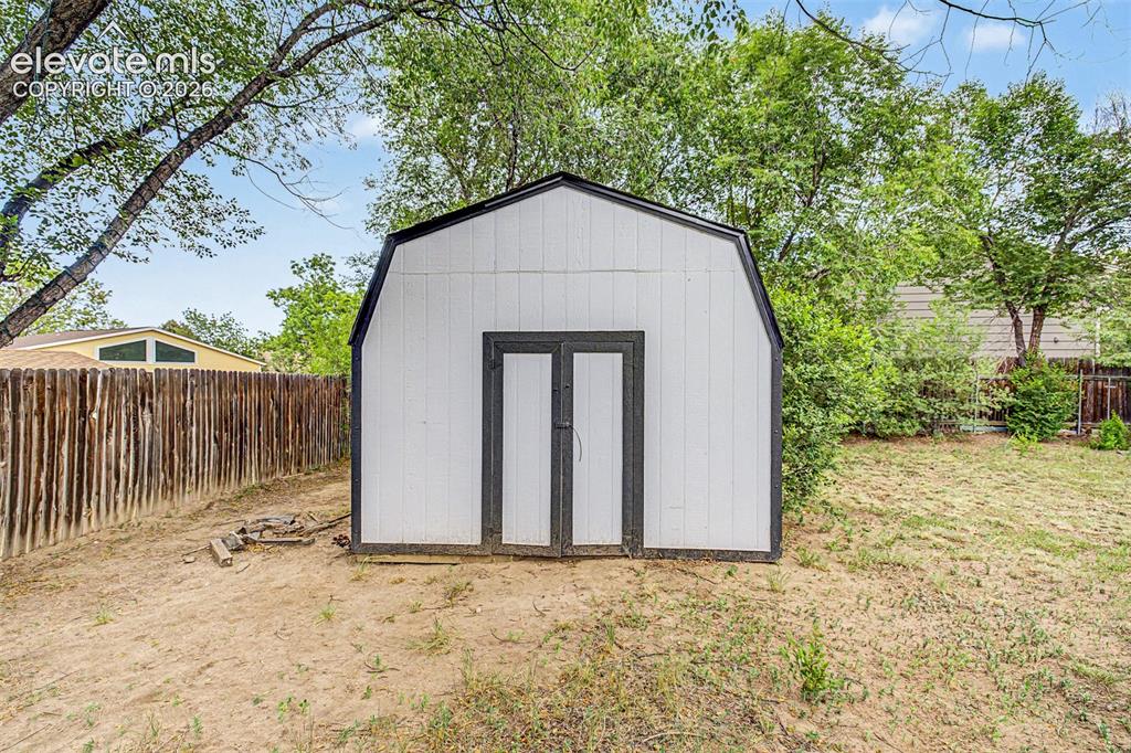 Image 32 of 44: Oversized storage shed with a gambrel roof and dark trim, featuring double 