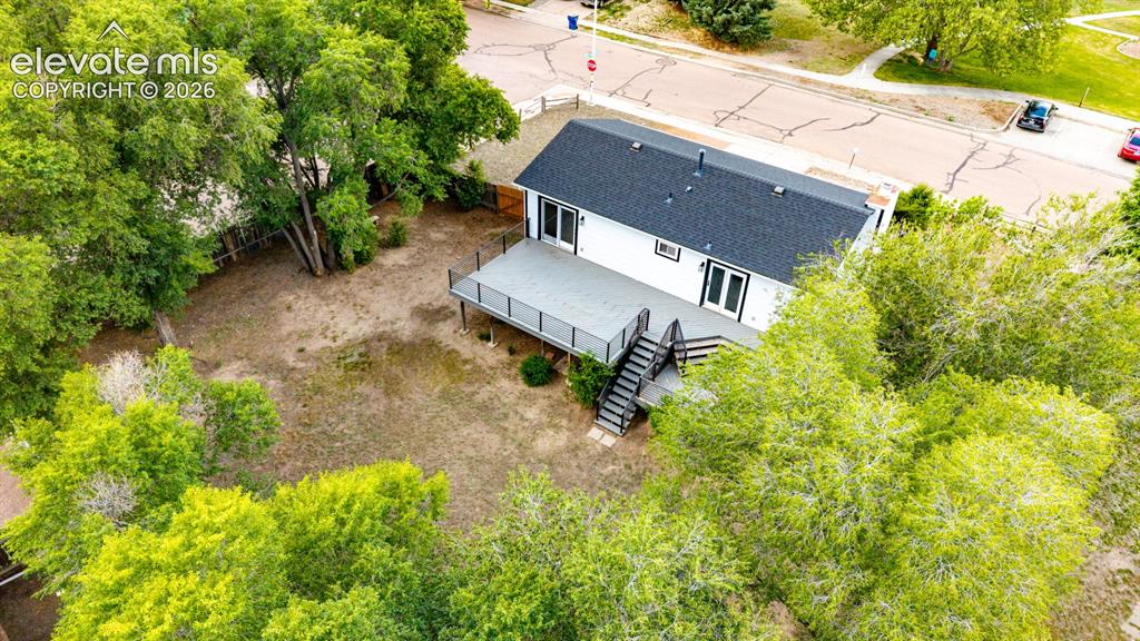 Image 35 of 44: Elevated deck with dark railings and steps, featuring a spacious backyard w