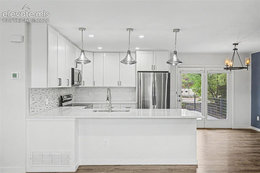 Image 7 of 44: Contemporary kitchen featuring white cabinetry, stainless steel appliances,