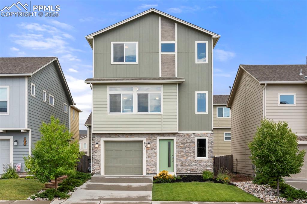 Caption: View of front of home with a garage, stone siding, and concrete driveway