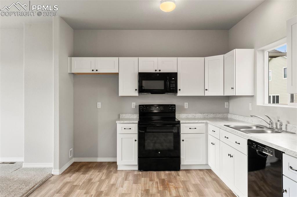 Image 10 of 22: Kitchen featuring black appliances, white cabinets, light countertops, and 